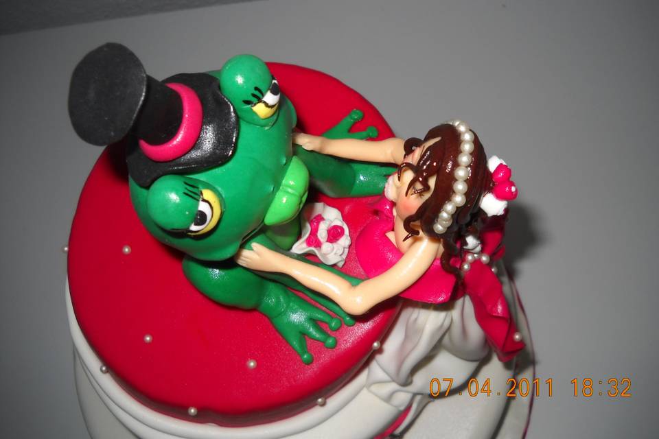 Noiva beijando sapo em topo de bolo